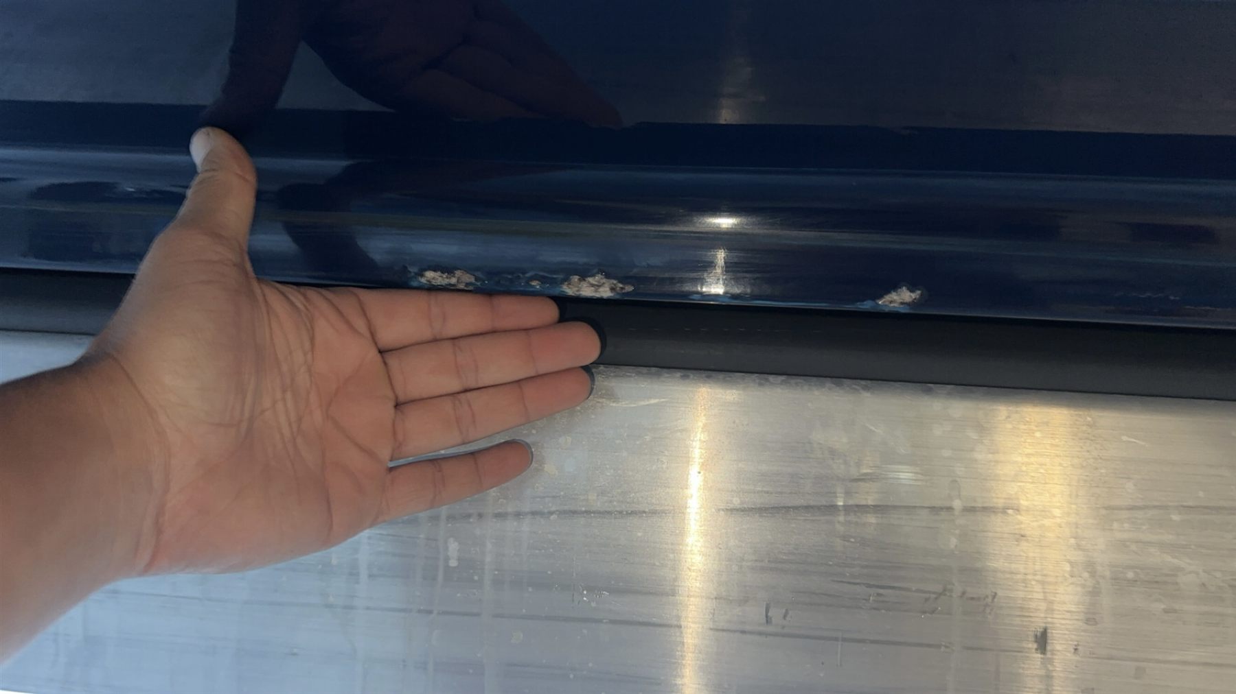 Close-up view of chipped dark-blue gel coat